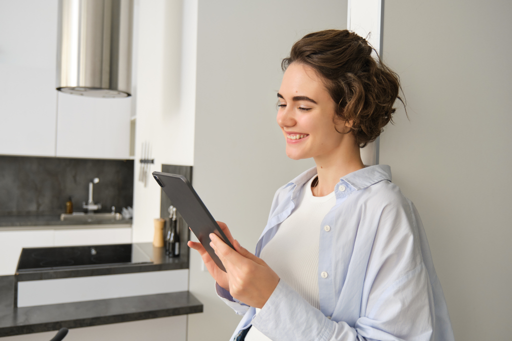 Portrait of woman smiling, looking at her digital tablet, reading message, watching videos online, working from home